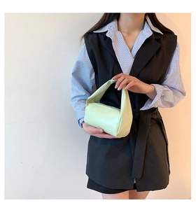 Detail of light green cylinder handbag with soft matte texture and unique single handle