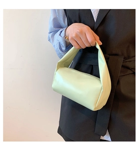 Detailed side view of a light green cylindrical handbag with smooth matte PU leather finish