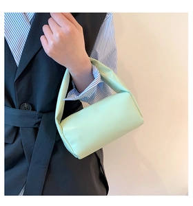 Close-up of mint green cylindrical handbag held by model in casual chic attire