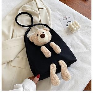 Detail shot of a black canvas tote bag featuring a cute 3D plush bear ornament