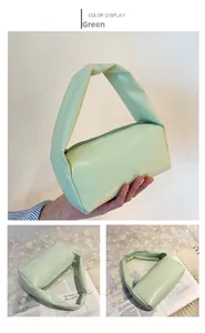 Detail view of light green matte leather handbag with wide top handle and zipper