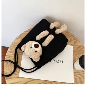 Detail of black canvas tote bag featuring a 3D plush bear and a long shoulder strap