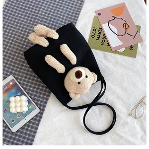 Detailed shot of black canvas bag with 3D teddy bear and adjustable shoulder strap