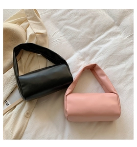 Detailed top view of black and pink cylinder handbags on a white aesthetic fabric background