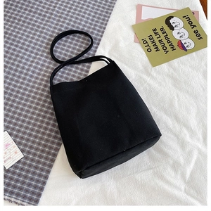 Minimalist black canvas tote bag shown from a top-down view on a patterned table