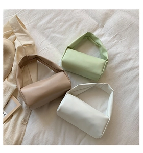 Three minimalist soft cylinder handbags in green, white, and khaki on white fabric
