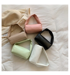 Top view of five soft PU cylinder handbags in pastel colors on white fabric