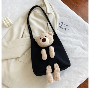 Detail of black canvas tote bag with a 3D plush bear on a white blazer background