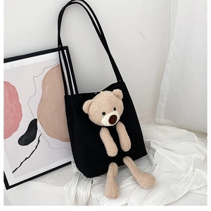 Detail of black canvas tote featuring a 3D plush teddy bear made of soft beige fleece