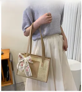 Détail du sac seau en paille avec nœud en dentelle florale et empiècement en cuir