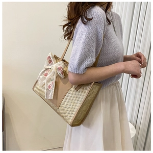 Dettaglio della borsa in paglia con elegante ricamo in pizzo e fiocco a rosa rosa