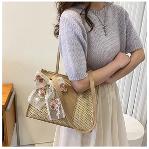 Dettaglio borsa tote in paglia con fiocco in pizzo floreale e rifiniture in pelle