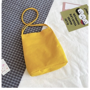 Detail view of the bright yellow canvas tote bag with shoulder strap on textured fabric