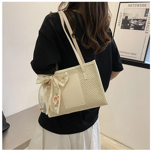 Dettaglio della borsa tote intrecciata con fiocco in pizzo floreale e tracolla in pelle