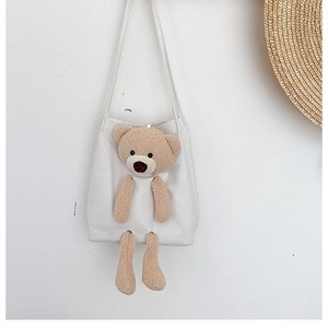 Detailed close-up of a white canvas tote bag featuring a 3D plush brown bear ornament