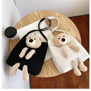 Close-up of canvas bags with 3D plush teddy bear decoration on a wooden table