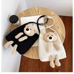 Detailed flat lay of black and white canvas crossbody bags with plush 3D teddy bears