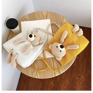 Detail view of canvas tote bags with cute 3D plush teddy bear ornaments in beige and yellow