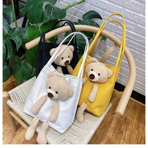 Detailed shot of canvas tote bags with plush bear toys in white, yellow, and black colors