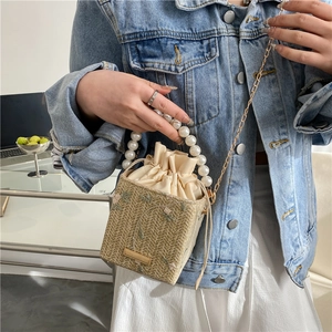 Woven straw bucket bag with floral embroidery, pearl handle and gold chain strap