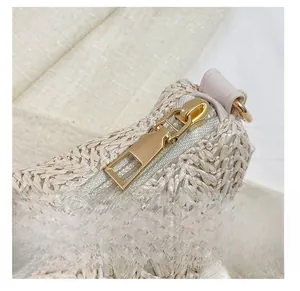 Close-up of smooth gold metal zipper and pink faux leather trim on woven straw tote bag