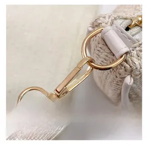 Detail of detachable shoulder strap with gold metal buckle on woven tote bag