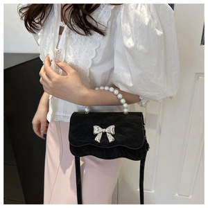 Detail of velvet handbag with silver bow buckle and elegant pearl handle strap