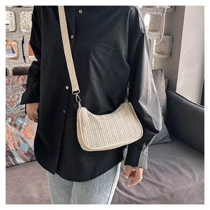 Detailed view of cream straw crescent bag with wide canvas strap and gold hardware
