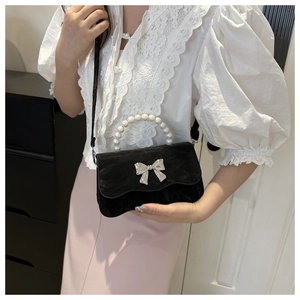 Detail of black velvet crossbody bag with pearl handle and silver bow buckle
