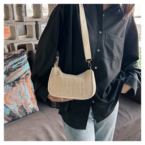 Detail of beige straw crescent tote bag with herringbone weave and wide textile strap