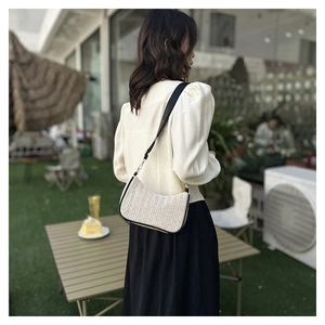 Close-up of contrast straw shoulder bag with black leather trim in an outdoor cafe setting