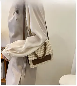 Détail du sac cabas en paille tressée avec rabat en cuir brun et chaîne en résine