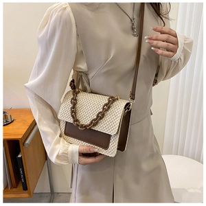 Détail du sac cabas en paille tissée avec rabat en cuir brun et chaîne chic