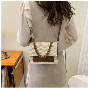 Détail du sac bandoulière en paille beige avec poche cuir marron porté par un modèle