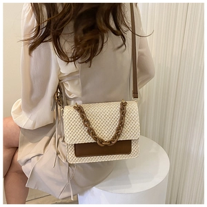 Détail du sac bandoulière en paille d'été avec chaîne en acrylique et rabat en cuir
