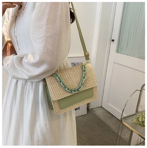 Détail du sac bandoulière d'été en paille avec garniture en cuir vert et grosse chaîne