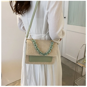 Mannequin portant un sac bandoulière en paille tissée avec rabat en cuir vert