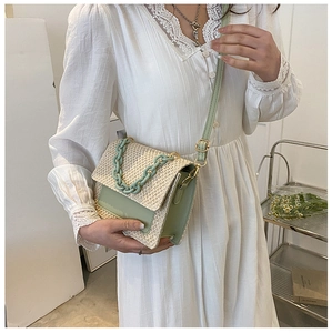 Détail du sac à bandoulière en paille tissée avec rabat en cuir vert et chaîne décorative