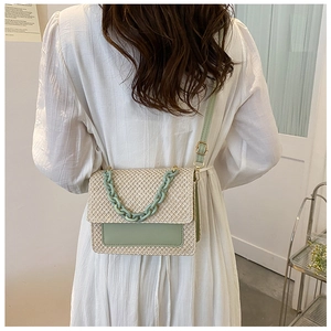 Sac bandoulière en paille avec cuir vert montré sur l'épaule d'un mannequin
