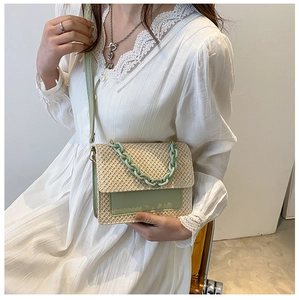 Détail de la texture en paille tressée et chaîne vert menthe sur robe en dentelle