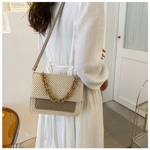 Sac bandoulière tissé beige avec chaîne en résine porté par un mannequin pour taille