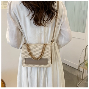 Détail du sac cabas tissé beige avec écusson en cuir marron et poignée chaîne sur modèle
