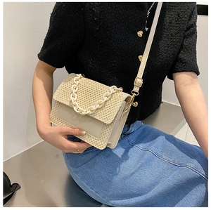 Détail d'un sac bandoulière en paille avec chaîne crème et rabat en similicuir