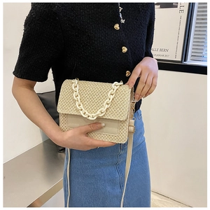 Gros plan d'un sac cabas tissé beige avec chaîne en résine et bandoulière en cuir