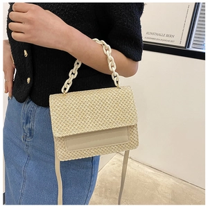 Détail du sac tissé crème avec poignée en chaîne épaisse et rabat en cuir lisse élégant