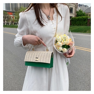 Détail du sac bandoulière en cuir vert et paille avec chaîne dorée et poignée en métal