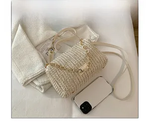 Close-up of beige woven crossbody bag with golden flower chain and leather strap details