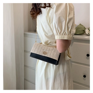 Détail du sac bandoulière en cuir noir et tissage beige avec chaîne dorée élégante