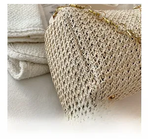 Close-up of cream woven straw bag detail with gold metal chain and textured craftsmanship