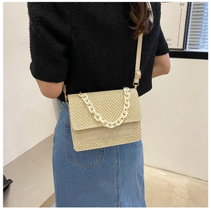 Détail du sac bandoulière en paille beige avec chaîne en résine et cuir
